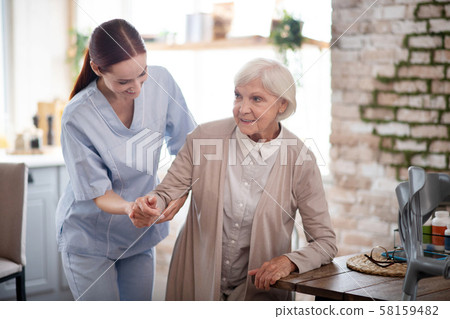 Caregiver smiling while helping aged woman to walk Caregiver smiling while helping aged woman to walk 58159482
