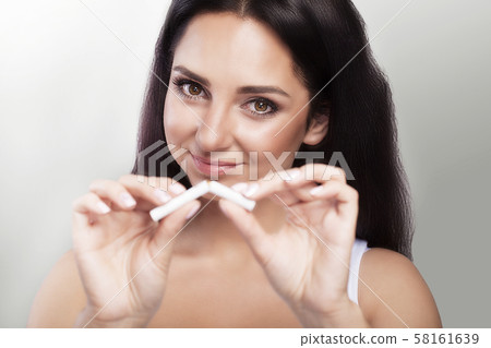 A woman tore cigarettes in her hands. Macro photo. Against smoking The concept of protecting the A woman tore cigarettes in her hands. Macro photo. Against smoking The concept of protecting the 58161639