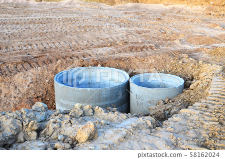 Installation of concrete sewer wells in the ground at the construction site.  58162024
