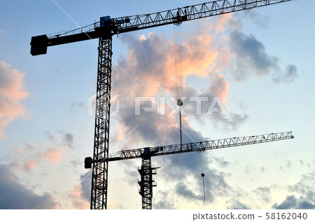 Jib construction tower crane and new residential buildings at a construction site on the sunset Jib construction tower crane and new residential buildings at a construction site on the sunset  58162040