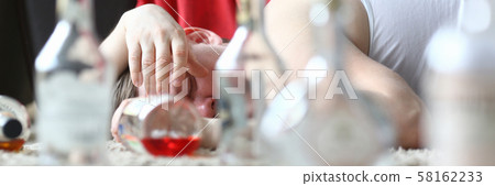 Drunken man lying among pile of empty Drunken man lying among pile of empty 58162233