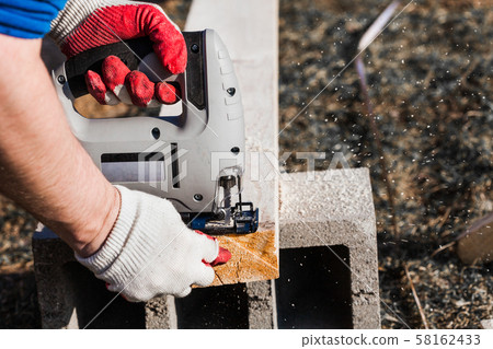 a man saws an electric jigsaw board 58162433