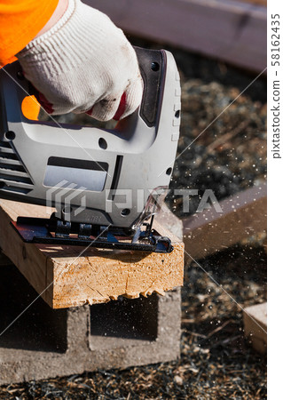 a man saws an electric jigsaw board 58162435