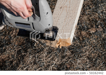 a man saws an electric jigsaw board a man saws an electric jigsaw board 58162442