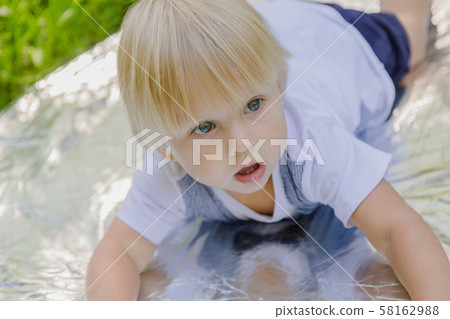 Happy little boy on a green lawn in a park. Happy little boy on a green lawn in a park. 58162988