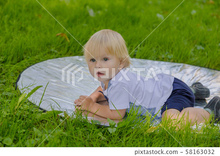 Happy little boy on a green lawn in a park. Happy little boy on a green lawn in a park. 58163032