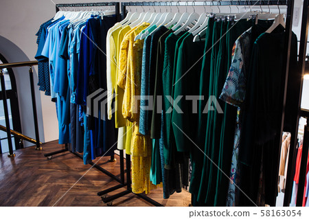Close-up view of various stylish clothes hanging on hangers in boutique. Clothes Close-up view of various stylish clothes hanging on hangers in boutique. Clothes 58163054