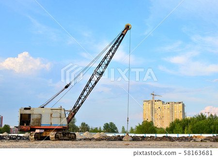 Large crawler crane or dragline excavator with a heavy metal wrecking ball on a steel cable. Large crawler crane or dragline excavator with a heavy metal wrecking ball on a steel cable. 58163681