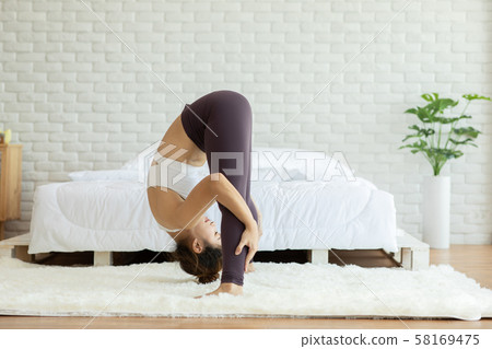 Athletic Asian woman practice yoga Spread foot stretching pose or Prasarita Padottanasana pose to meditation in bedroom after wake up in the morning Feeling so comfortable and relax,Healthcare Concept Athletic Asian woman practice yoga Spread foot stretching pose or Prasarita Padottanasana pose to meditation in bedroom after wake up in the morning Feeling so comfortable and relax,Healthcare Concept 58169475