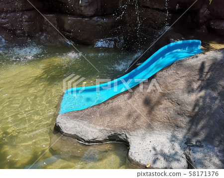 A blue water slider in pool with modeled waterfall. A blue water slider in pool with modeled waterfall. 58171376