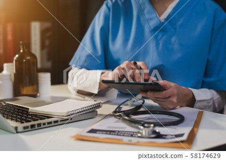 Doctor working on desk with laptop computer and paperwork in the office. Medical and doctor concept. Doctor working on desk with laptop computer and paperwork in the office. Medical and doctor concept. 58174629