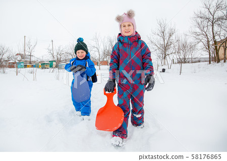 Happy boy and girl walking on a hill sledding in Happy boy and girl walking on a hill sledding in 58176865
