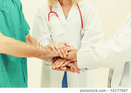 Doctor, surgeon and nurse join hands together. 58177807