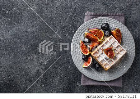 Traditional Belgian waffles with powdered sugar grapes and figs. Cozy homemade Breakfast. Gray concrete background. Copy space. Traditional Belgian waffles with powdered sugar grapes and figs. Cozy homemade Breakfast. Gray concrete background. Copy space. 58178111