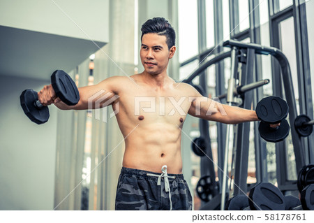 Muscular man bodybuilder training with dumbbells. 58178761