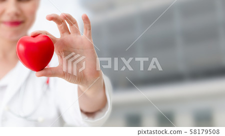 Doctor holding a red heart at hospital office. Doctor holding a red heart at hospital office. 58179508