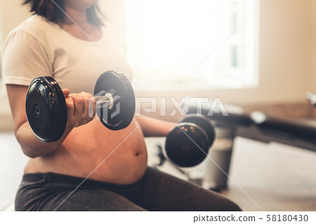 Active pregnant woman exercise in fitness center. Active pregnant woman exercise in fitness center. 58180430