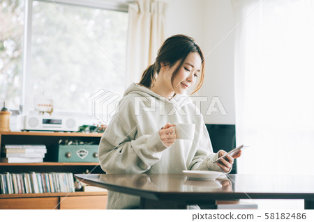 A woman who drinks coffee in a room 58182486
