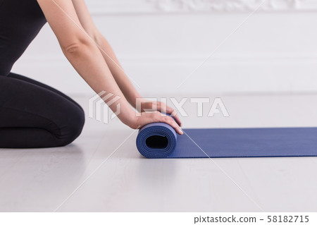 Closeup of young women's hands rolling up the blue carpet 58182715