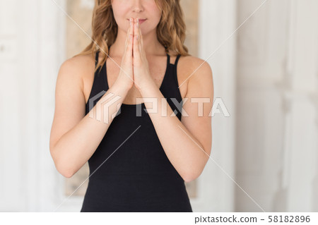 Closeup of young women holding her palm together on her chest 58182896