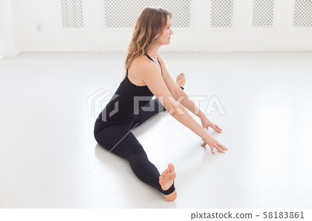 Blond sporty woman doing splits in white empty room 58183861
