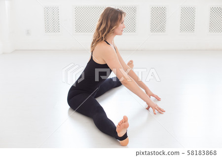 Blond sporty woman doing splits in white empty room Blond sporty woman doing splits in white empty room 58183868