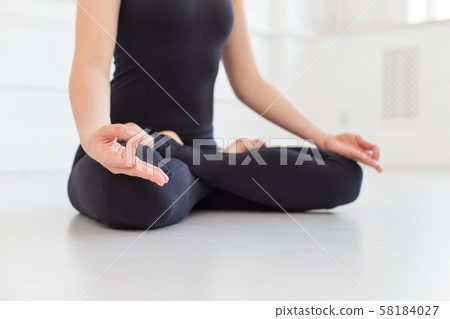 Beautifull woman in black sport outfit sits on white bare floor. Selective focus Beautifull woman in black sport outfit sits on white bare floor. Selective focus 58184027