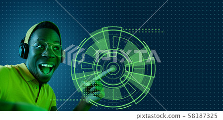 Young african-american man's touching virtual reality in neon light Young african-american man's touching virtual reality in neon light 58187325