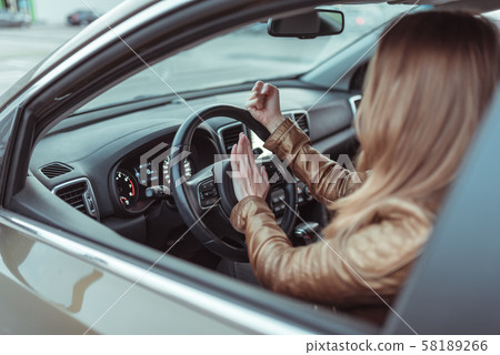 Woman driving a car. He presses signal on steering wheel of car, gesture with his fist, aggression Woman driving a car. He presses signal on steering wheel of car, gesture with his fist, aggression 58189266