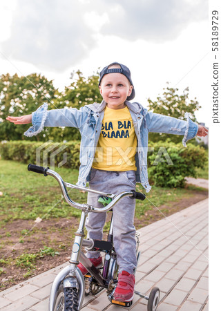 little boy, child of 3-5 years old, happy to ride bicycle, summer spring autumn day in city park 58189729