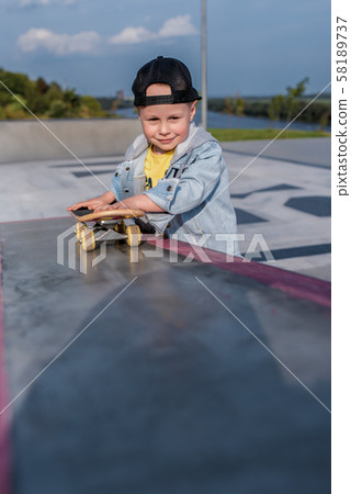 little boy of 3.5 years old, child smiles, plays, has rest, on summer autumn day in city park, fun 58189737