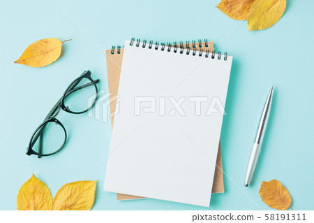 notebook on cyan background with autumn leaves 58191311