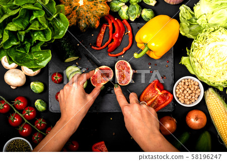 Female hands cut vegetables on a black background. Cooking vegetarian food. Top view. 58196247