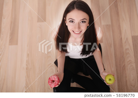 Diet. Woman Measuring Body Weight On Weighing Scale Holding Donut and apple. Sweets Are Unhealthy 58196770