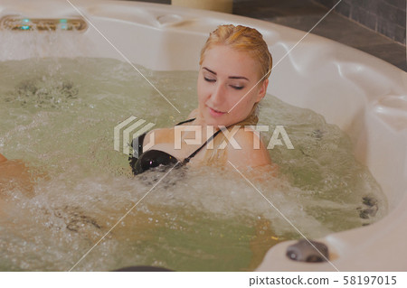 Young beautiful woman relaxes in a jacuzzi. 58197015