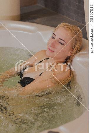 Young beautiful woman relaxes in a jacuzzi. Young beautiful woman relaxes in a jacuzzi. 58197018