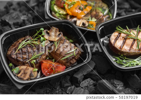 Composition of three grilled dishes in to go boxes 58197019