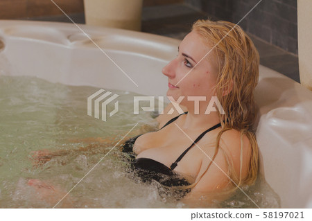 Young beautiful woman relaxes in a jacuzzi. Young beautiful woman relaxes in a jacuzzi. 58197021