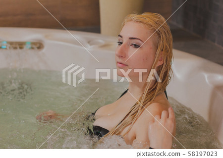 Young beautiful woman relaxes in a jacuzzi. Young beautiful woman relaxes in a jacuzzi. 58197023