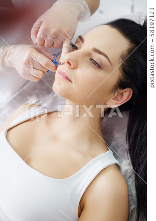 The doctor-cosmetologist makes the procedure Microcurrent therapy of the facial skin of a beautiful The doctor-cosmetologist makes the procedure Microcurrent therapy of the facial skin of a beautiful 58197121