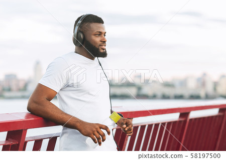 Dreamy black athletic guy resting on city bridge 58197500