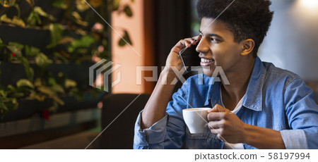 Black guy talking on mobile phone and smiling at cafe 58197994