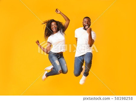 Joyful black couple jumping up and down 58198258