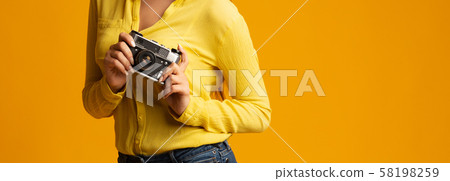 Unrecognizable millennial girl holding retro camera on yellow background, cropped 58198259