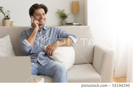 Positive Man Talking By Cellphone Sitting On Couch At Home Positive Man Talking By Cellphone Sitting On Couch At Home 58198290