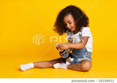 Child girl playing with microscope, yellow background Child girl playing with microscope, yellow background 58198912