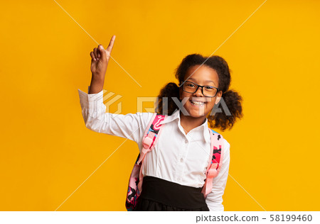 African American Schoolgirl Pointing Finger Up On Yellow Background African American Schoolgirl Pointing Finger Up On Yellow Background 58199460