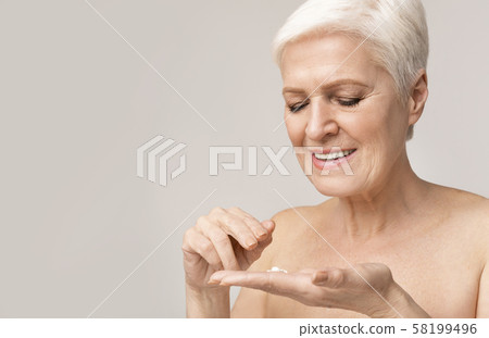 Happy senior woman applying anti-wrinkle cream for skin Happy senior woman applying anti-wrinkle cream for skin 58199496