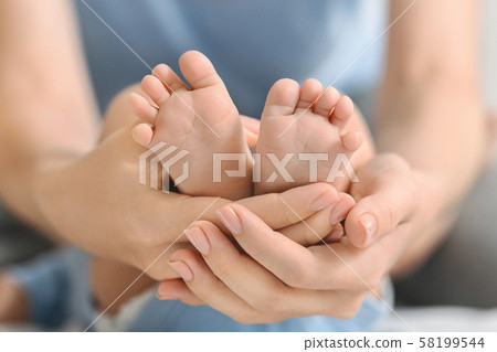 Newborn baby feet in mother's hands closeup 58199544