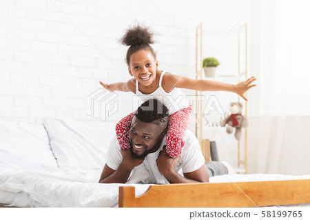 Cheerful african girl playing with father, flying like plane 58199765